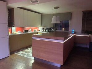 Cozinha moderna com ilha central, eletrodomésticos embutidos e luminária pendente.