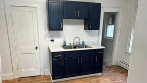 A kitchen with dark cabinets, a white countertop, and a wooden floor.