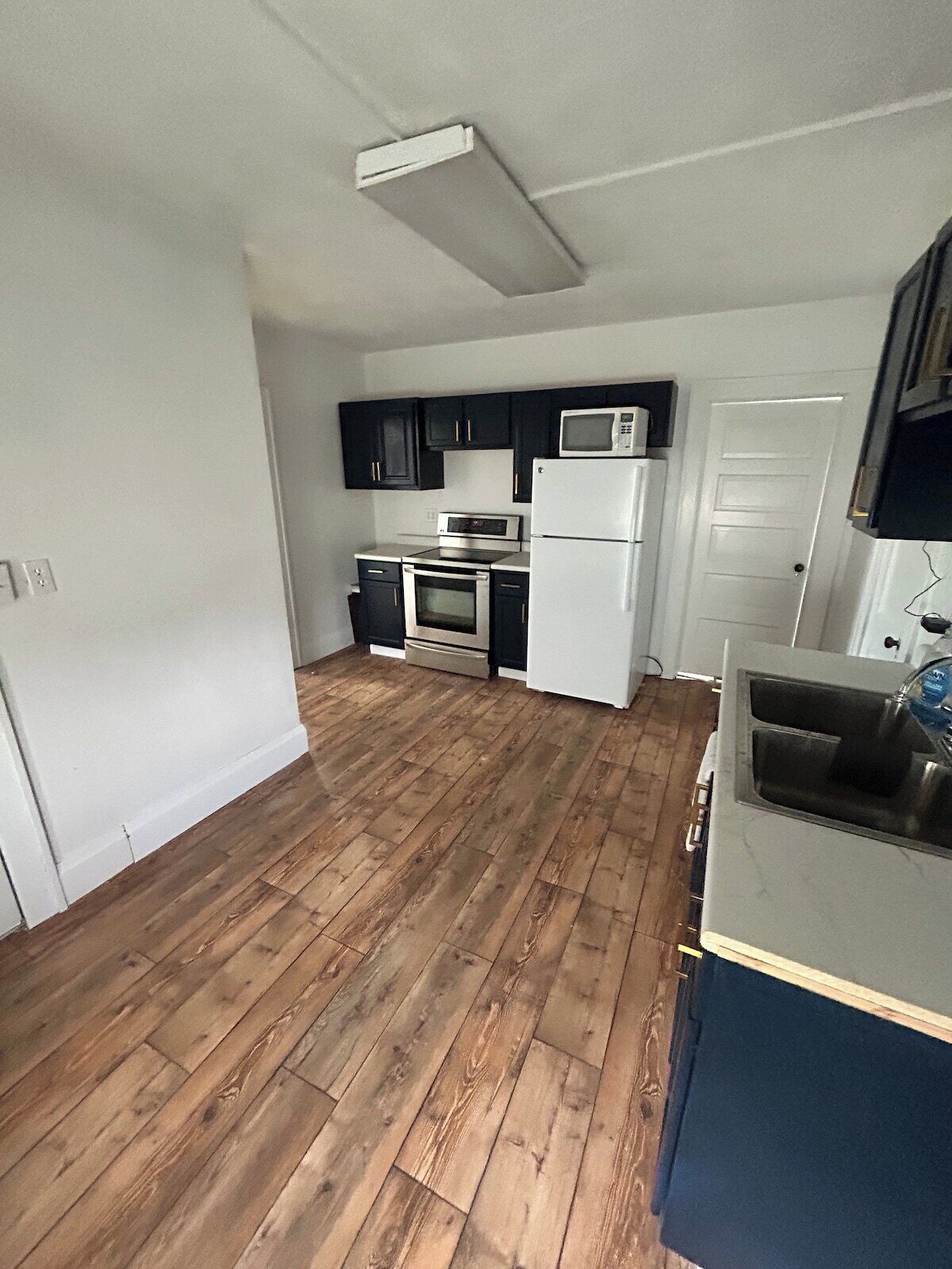 A kitchen with dark cabinets, a microwave, a refrigerator, and an oven.
