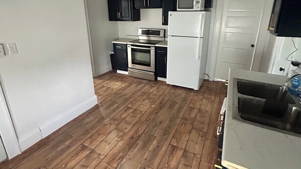 A kitchen with dark cabinets, a microwave, a refrigerator, and an oven.