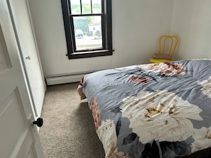 A bedroom with a bed, a window, a chair, and a door. - Bright Modern Bath & Cozy Living Oasis (Mountain Iron)