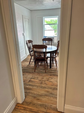 A dining area with a round table and four chairs, wooden flooring, and white walls. - Bright Modern Bath & Cozy Living Oasis (Mountain Iron)