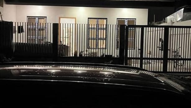A modern building with a gated entrance, a covered outdoor area, and a car parked in the foreground. - Cozy 3BR Home in Quezon City (Quezon City)