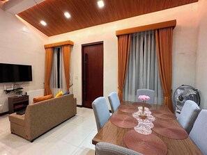A modern living room with a sofa, dining table, and chairs.
