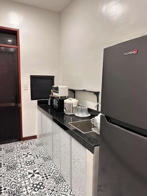 A compact kitchen with a refrigerator, a microwave, a coffee maker, and a sink.