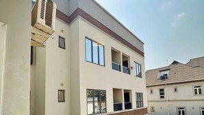 Een meerlaags woongebouw met balkons, een auto op de oprit, en een airconditioning op de buitenmuur.