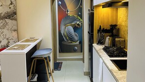Een smalle keuken met een eethoek, een spoelbak en een fornuis.