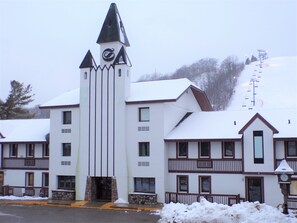 Ett hotell med flera våningar och ett centralt torn med en klocka, flera balkonger och en skidlift i bakgrunden.