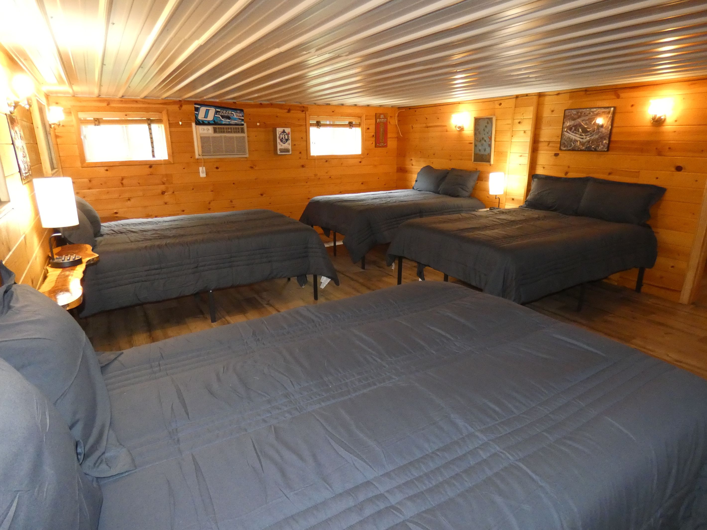 A cabin with three beds, a wooden interior, and a window.