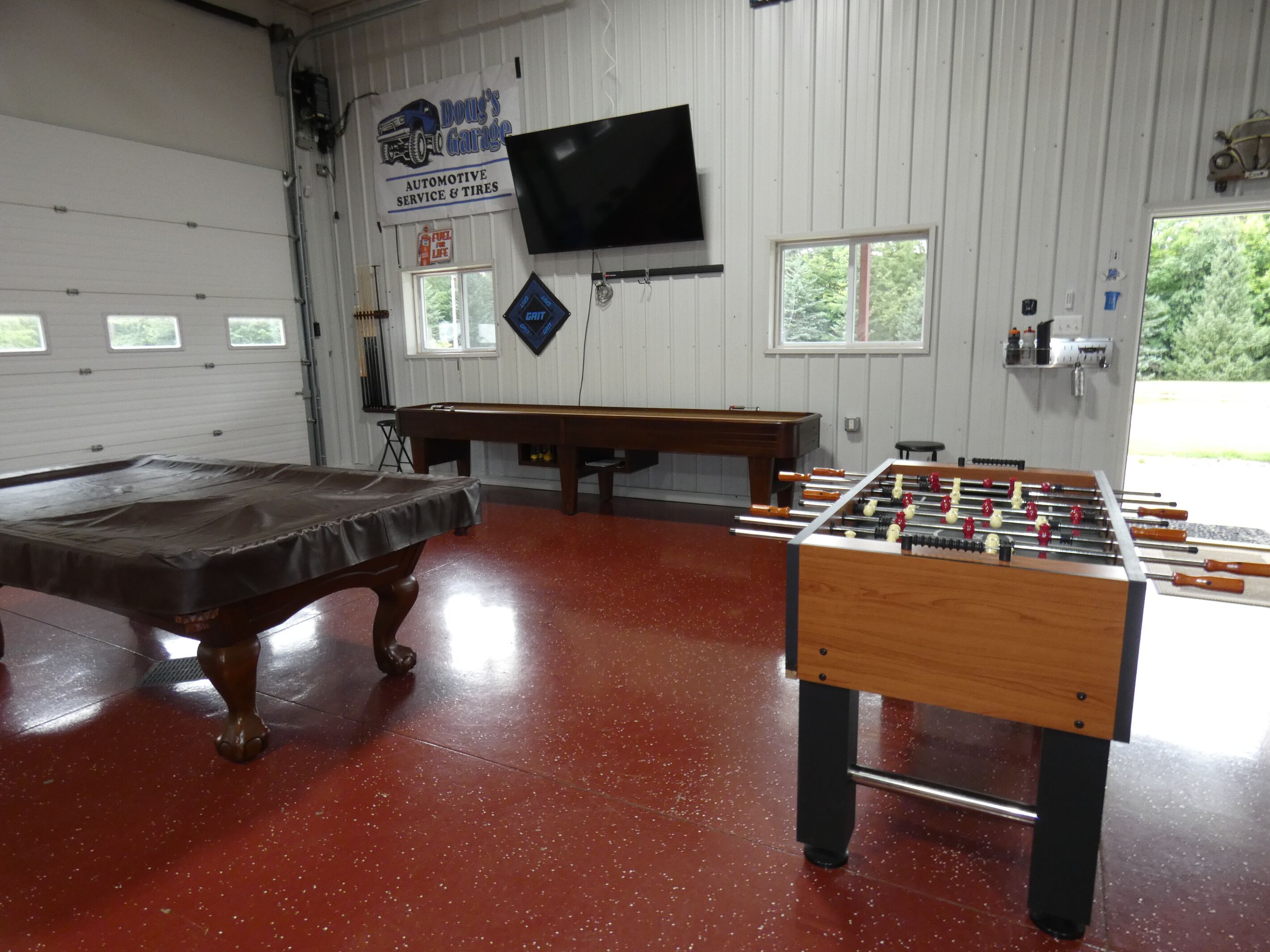 A room with a pool table, foosball table, and a billiards table.