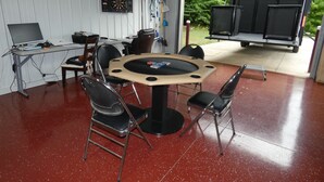 Quarto com dardos, um laptop e uma mesa com cadeiras.