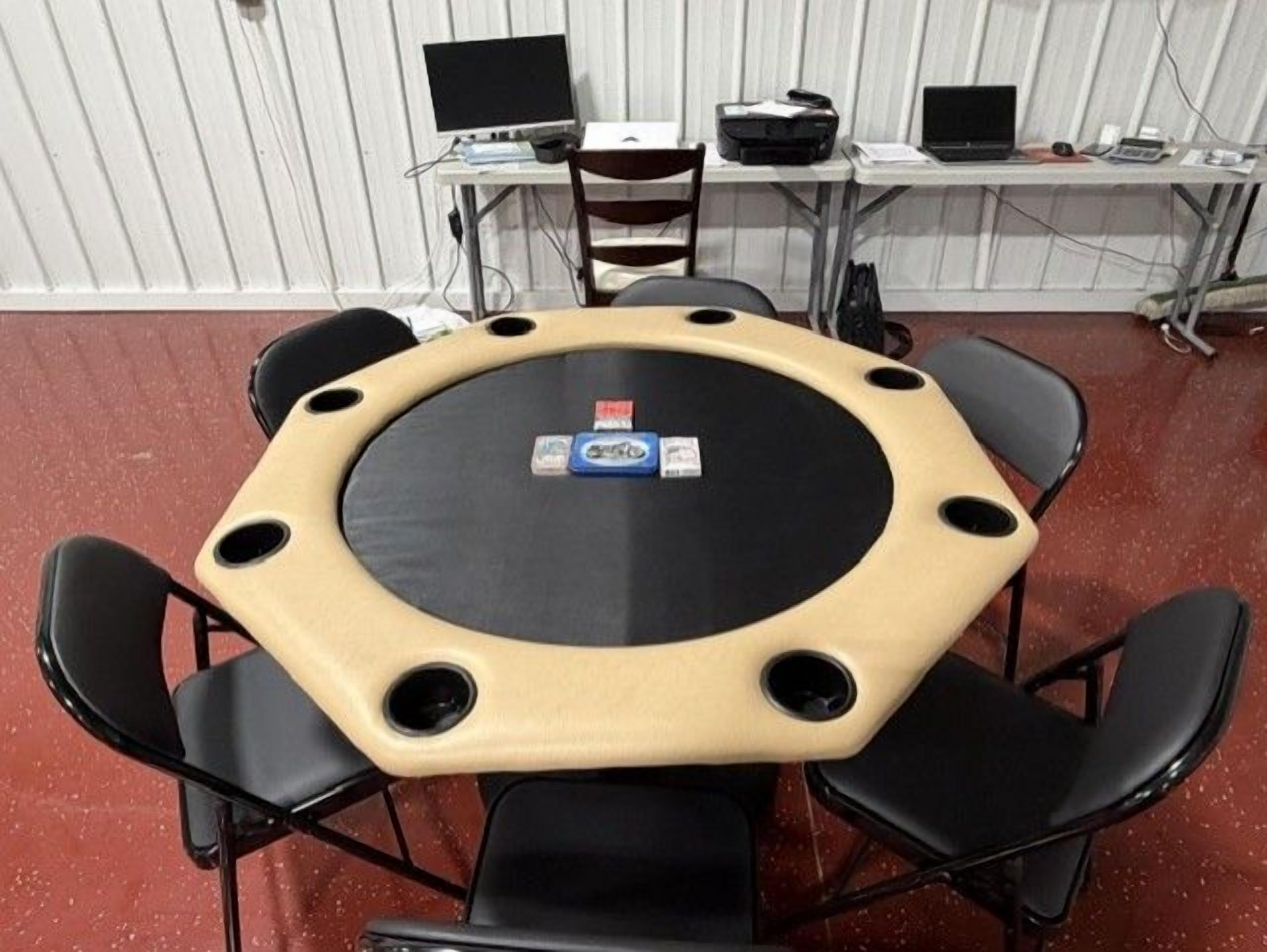 Una mesa redonda con superficie negra y bordes color beige, rodeada de sillas negras.