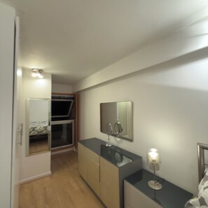 A compact bedroom with a bed, a bedside table, a mirror, and a nightstand. - Cosy City Apartment (London)
