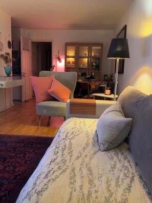 A living room with a sofa, armchair, and a coffee table. There is a dining area in the background with a table and chairs. - Cosy City Apartment (London)