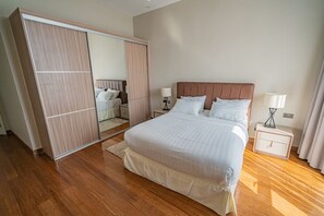Ein Schlafzimmer mit einem großen Bett, einem Kleiderschrank, Nachttischlampen und einem Nachttisch.