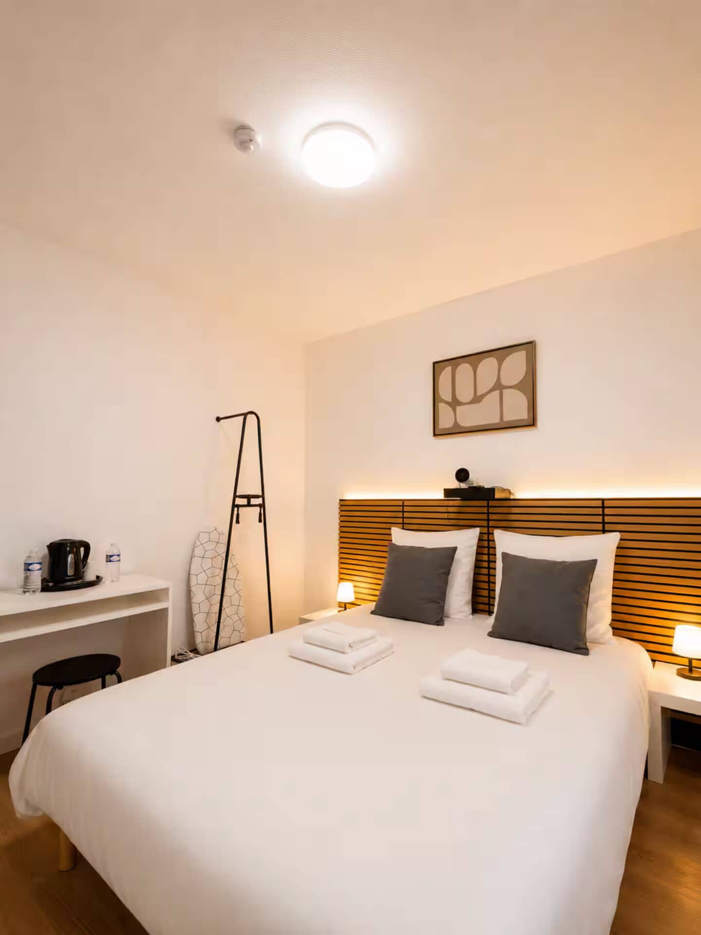 Una habitación de hotel con una cama grande, mesitas de noche, un escritorio y una silla.