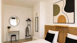 A modern hotel room with a large bed, a desk, and a mirror.