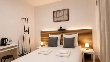 Una habitación de hotel con una cama grande, mesitas de noche, un escritorio y una lámpara en el techo.