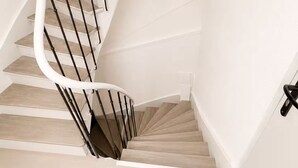 A spiral staircase with wooden steps and black railings.