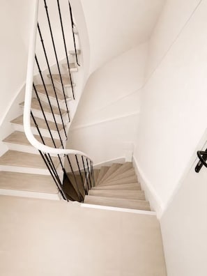 A spiral staircase with wooden steps and black railings.