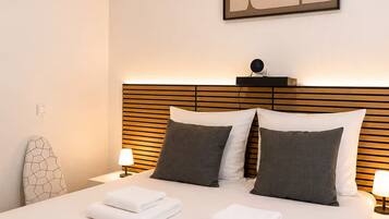Une chambre d’hôtel avec un lit parfaitement fait, deux lampes de chevet et un tableau abstrait moderne accroché au mur.
