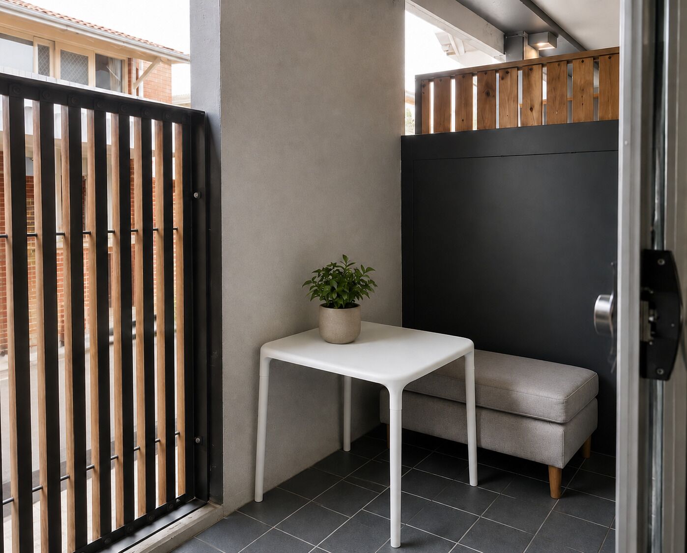 Une pièce d’angle avec une table blanche, un canapé gris et une plante en pot.
