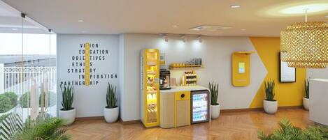 A modern reception area with a wooden floor, potted plants, a counter with a coffee machine, and a wall with motivational text.