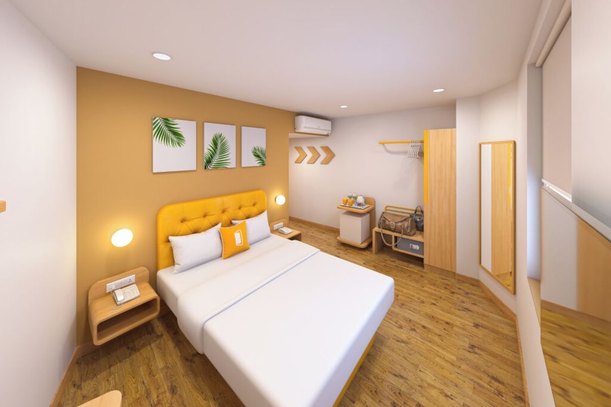 A modern hotel room with a large bed, bedside tables, a wardrobe, and a mirror.