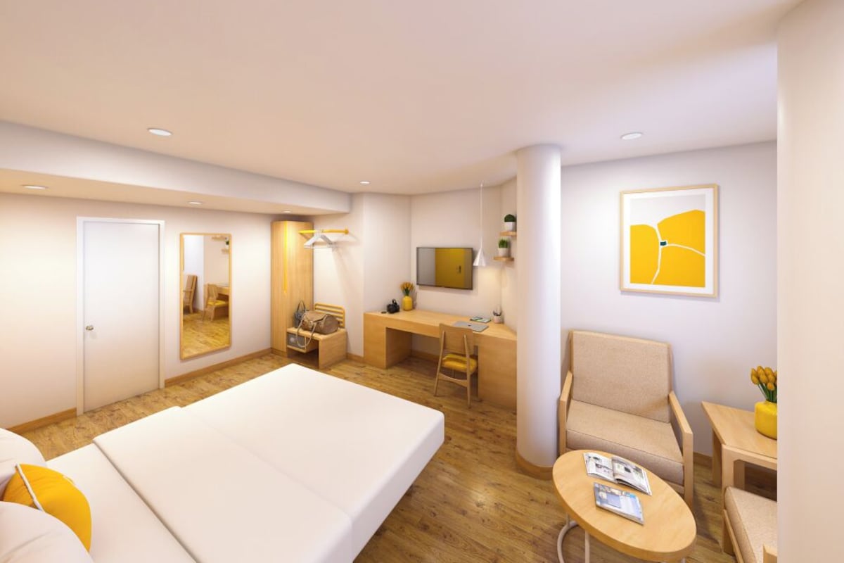A hotel room with a bed, desk, chair, and a small table.