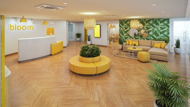 A modern lobby with a reception desk, seating area, and a green leafy wall.