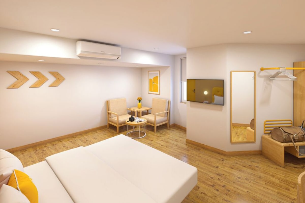 A hotel room with a bed, a seating area with chairs, a small table, a flat-screen TV, a mirror, and a coat rack.