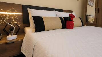 A neatly made bed with a white quilt, a wooden headboard, and a bedside table with a decorative tree light.