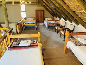 A rustic attic bedroom with wooden furniture, a large wardrobe, and a sloped ceiling. - Chenin Blanc Cottage (Ladismith)