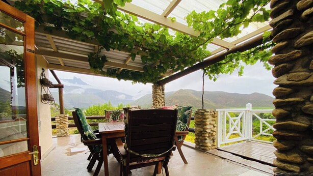 An outdoor patio with a table and chairs, a stone pillar, and a view of mountains.