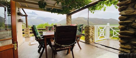 An outdoor patio with a table and chairs, a stone pillar, and a view of mountains.