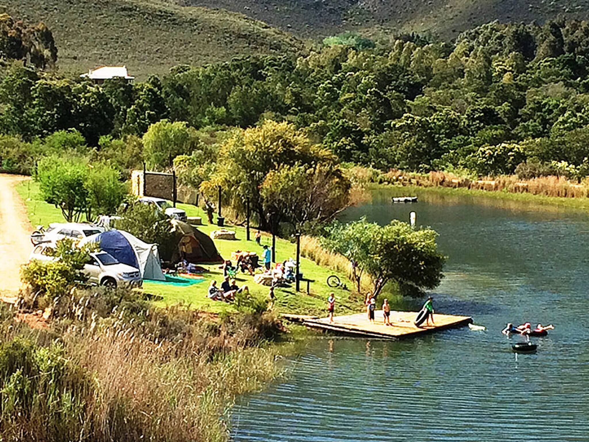 A lakeside campsite with tents, a dock, and a boat.