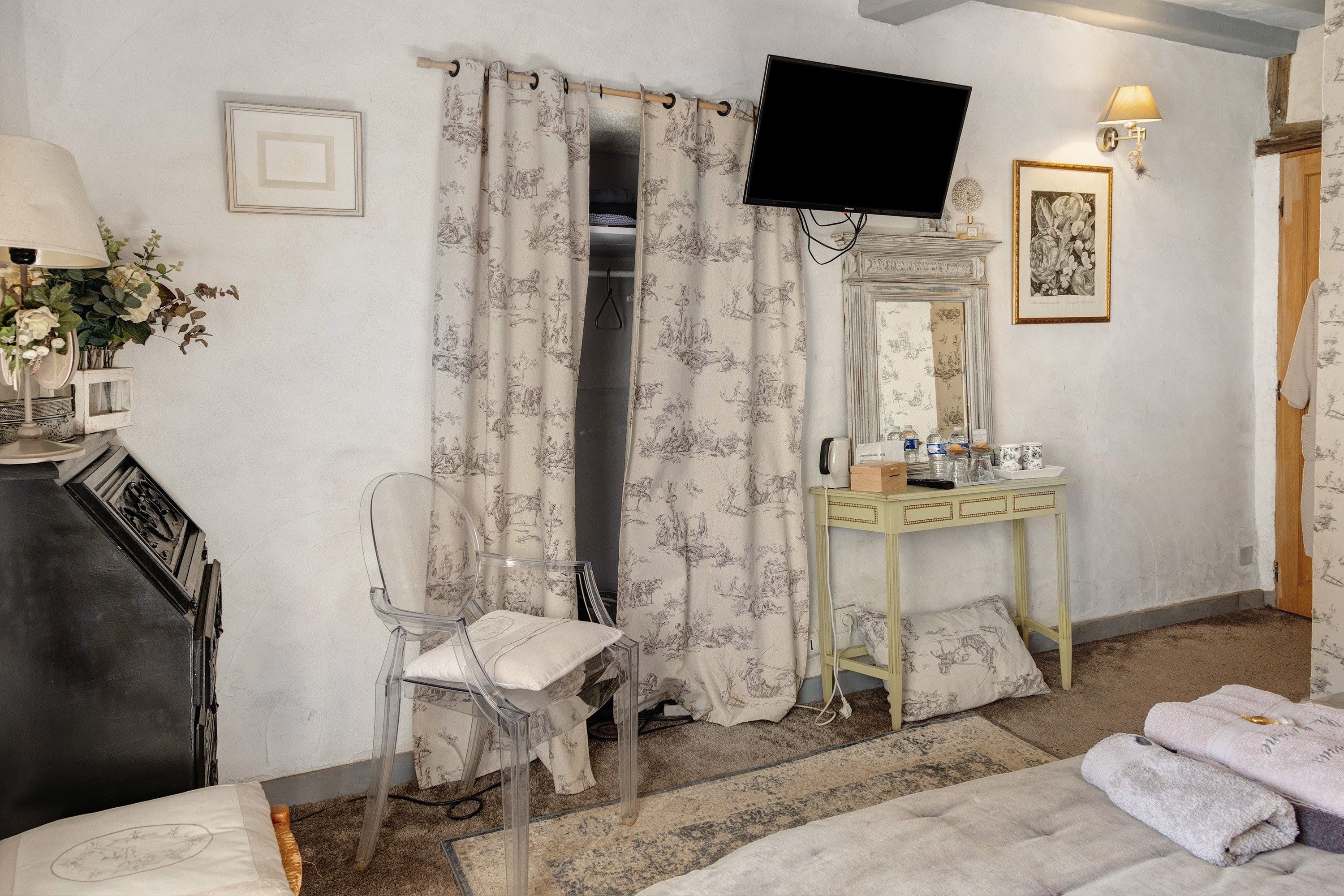 Een hotelkamer met een bed, een stoel, een kaptafel, een televisie en een douche.