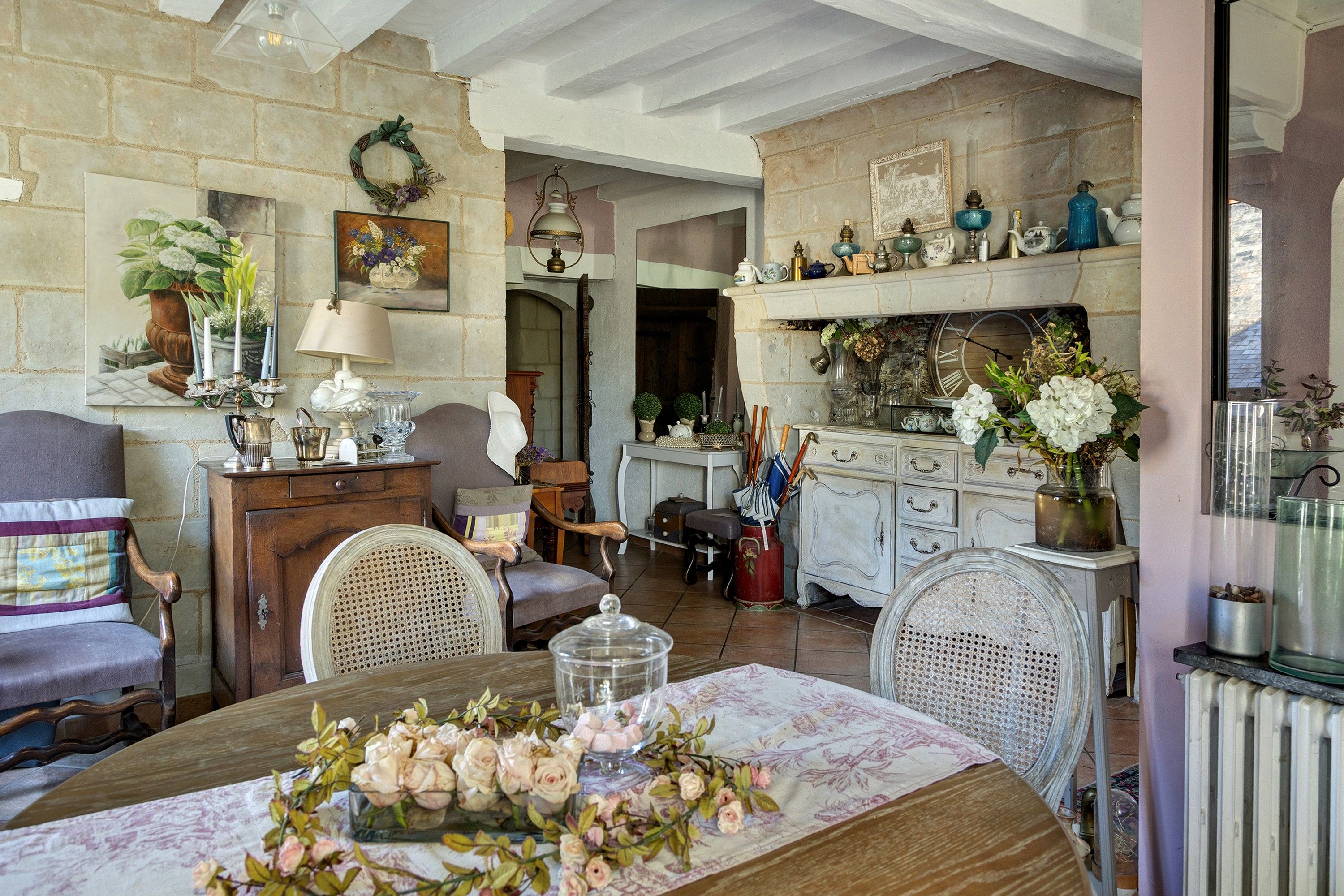 Een klassieke kamer met een eettafel voor vier personen, omringd door antiek meubilair en diverse decoratieve objecten.