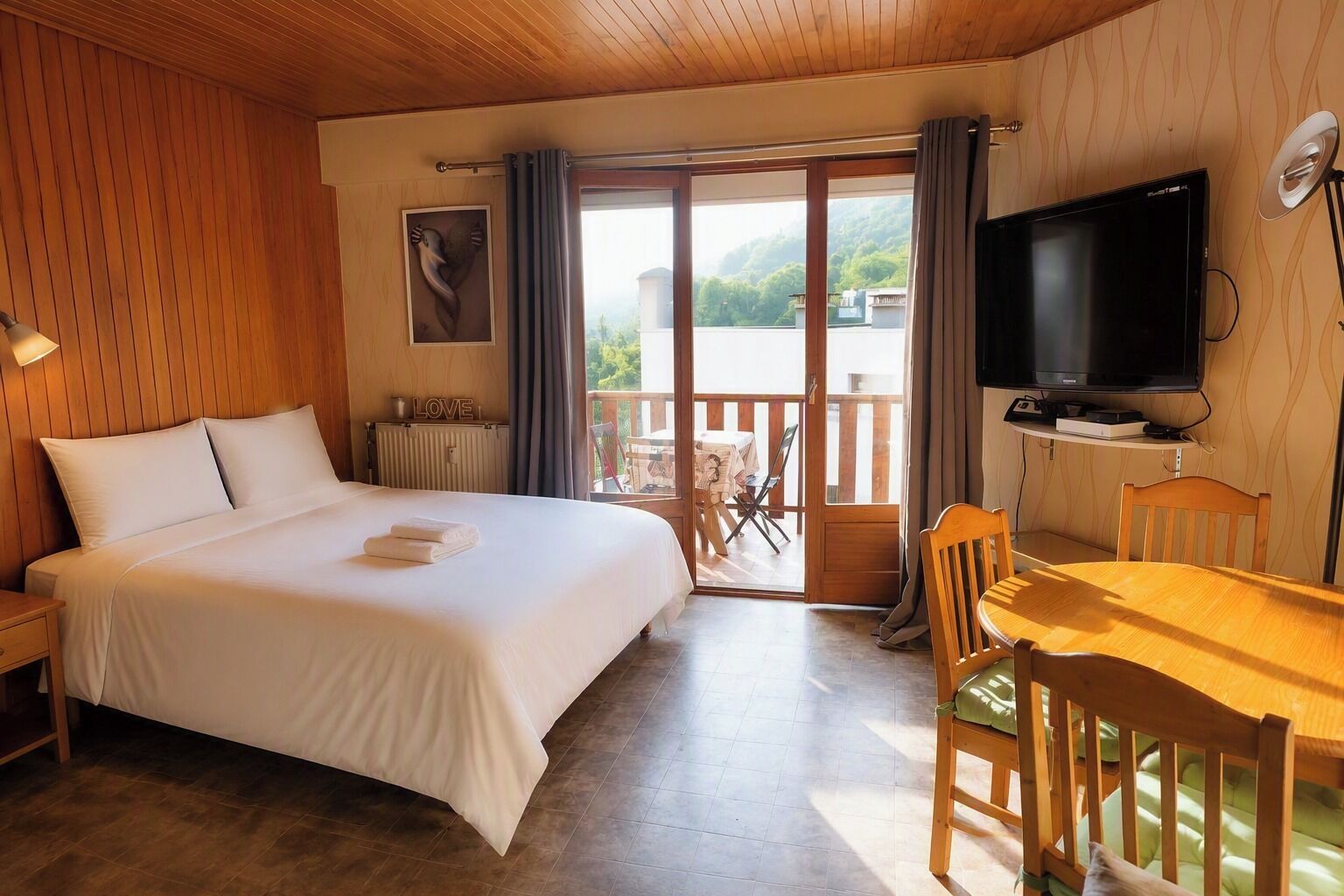 Una camera d'albergo con un letto, una televisione, un tavolo da pranzo e vista sull'esterno.