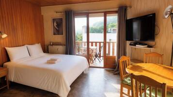 Una camera d'albergo con un letto, una televisione, un tavolo da pranzo e vista sull'esterno.