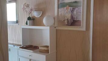 Une pièce avec une armoire blanche, un tableau encadré et une orchidée en pot.