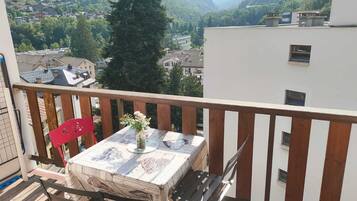 Un balcone con un tavolo, sedie e un vaso di fiori.