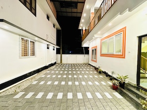 A courtyard with a checkered floor, potted plants, and a white building with orange trim. - Varkala Escape Beach Resort (Varkala)