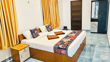 A hotel room with a bed, curtains, a wardrobe, and a bathroom door.