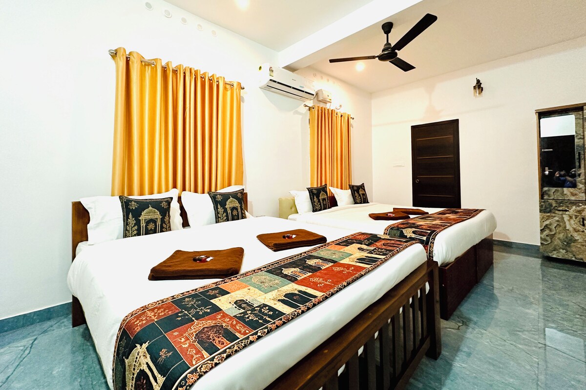 A hotel room with two beds, a ceiling fan, an air conditioning unit, and a large mirror.