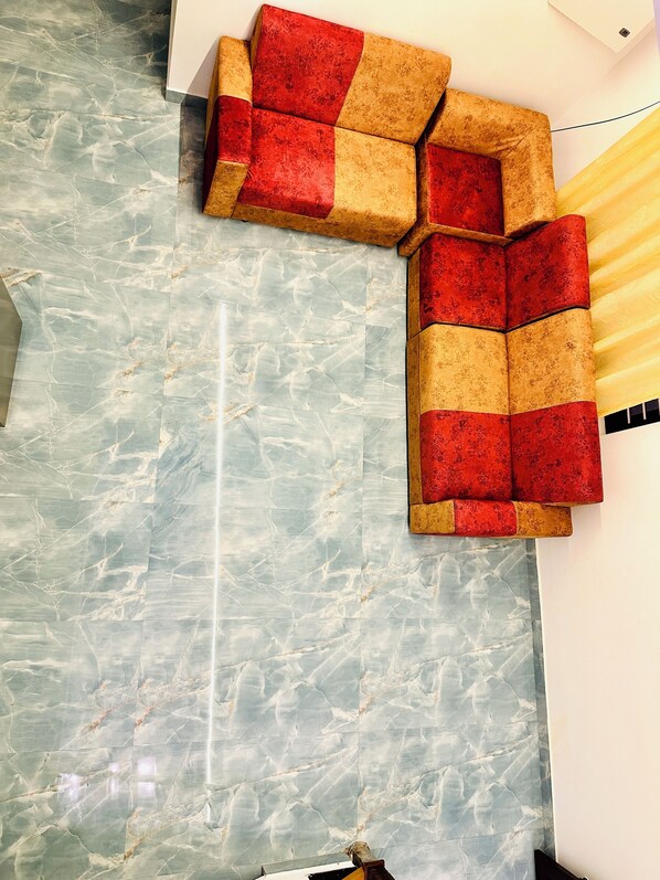 A room with a marble floor and a sectional sofa with a red and beige color scheme. - Varkala Escape Beach Resort (Varkala)