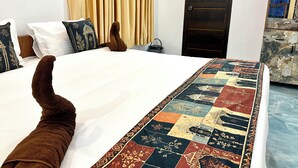 Una cama con una colcha estampada, cabecera de madera y una puerta oscura al fondo.