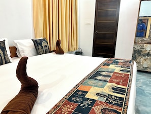 A bed with a patterned bedspread, a wooden headboard, and a dark door in the background. - Varkala Escape Beach Resort (Varkala)