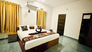 Habitación de hotel con cama, cortinas, aire acondicionado, una puerta y piso de baldosas.