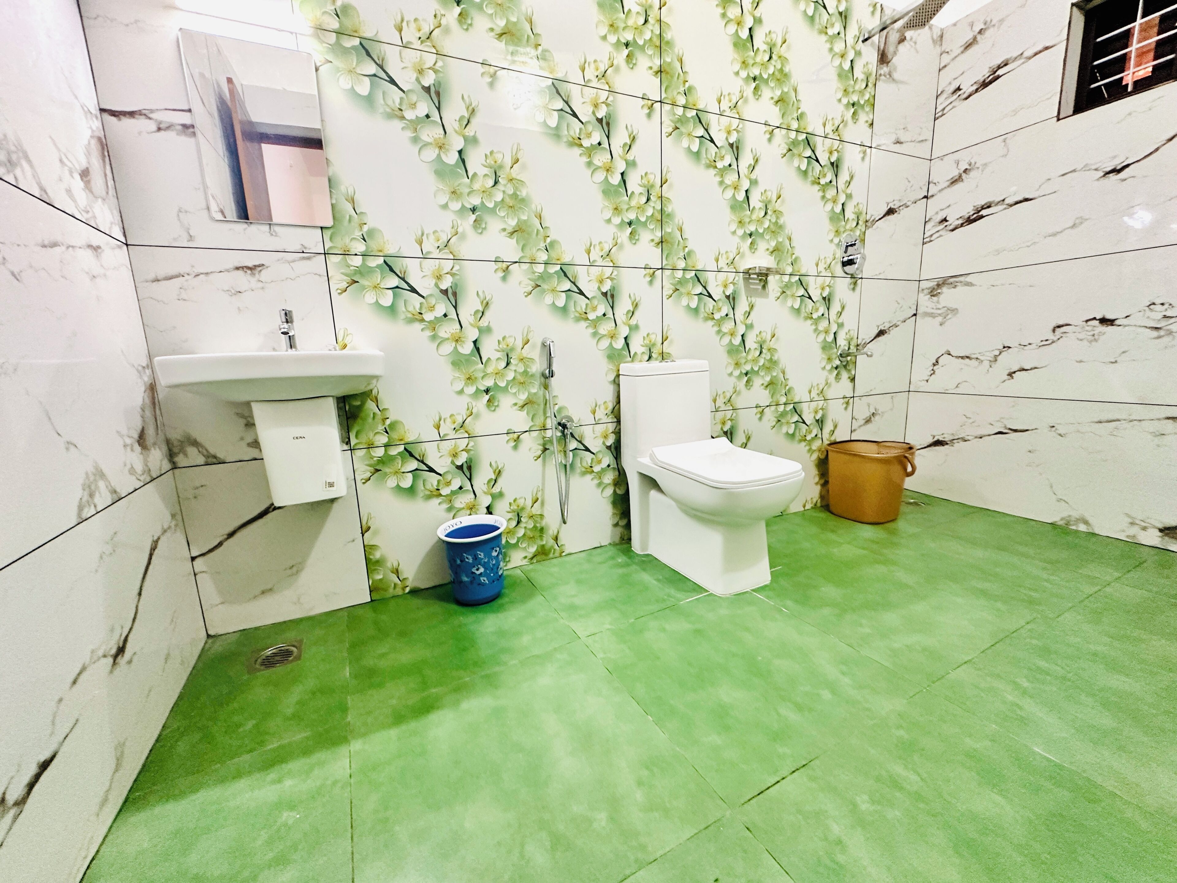 Een badkamer met toilet, wastafel en groene vloertegels.
